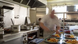 Una cocina industrial con electrodomésticos de acero inoxidable, un horno grande y un chef preparando comida.