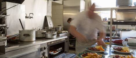 A commercial kitchen with stainless steel appliances, a large oven, and a chef preparing food.