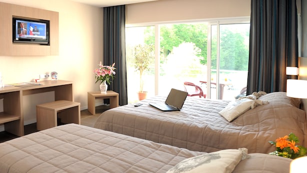 Habitación de hotel con dos camas, un escritorio, una computadora portátil, un televisor y vista al exterior.