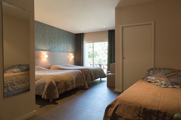 A hotel room with two beds, a large window, and a door.