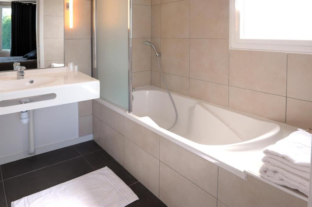 A modern bathroom with a white sink, a bathtub, and a mirror.