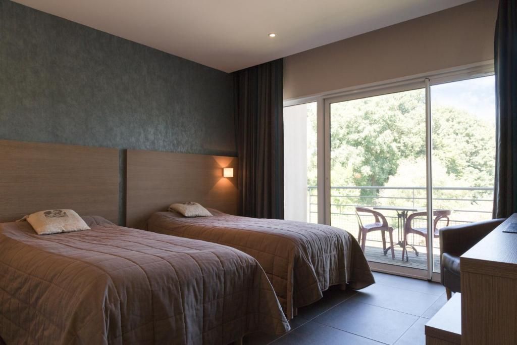 Een hotelkamer met twee bedden, een bureau en een balkon met stoelen.