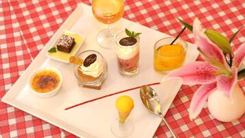 A tray with various desserts and a glass of orange juice on a checkered tablecloth.