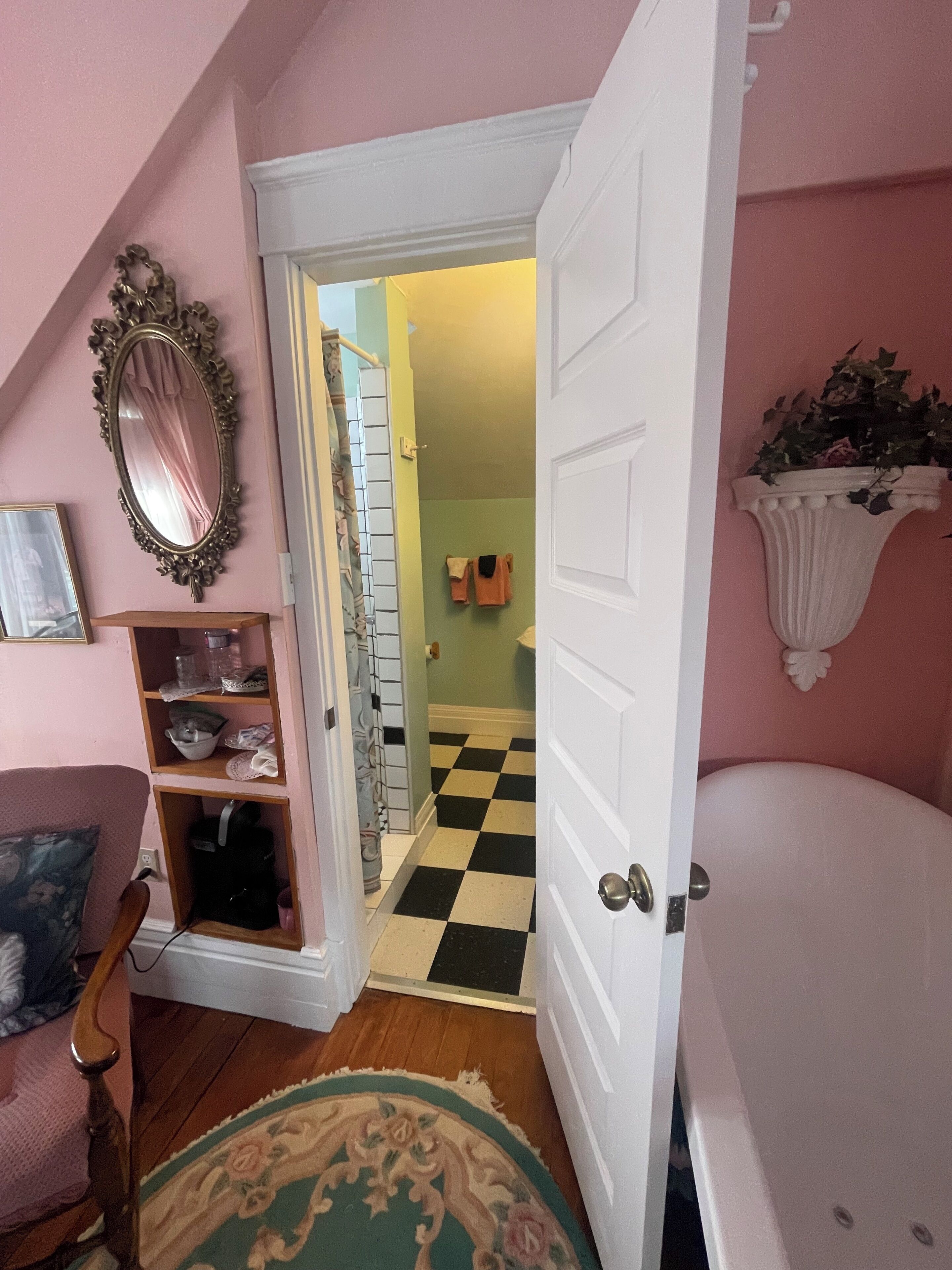 A room with a checkered floor, a white door, a mirror, and a shelf with items.