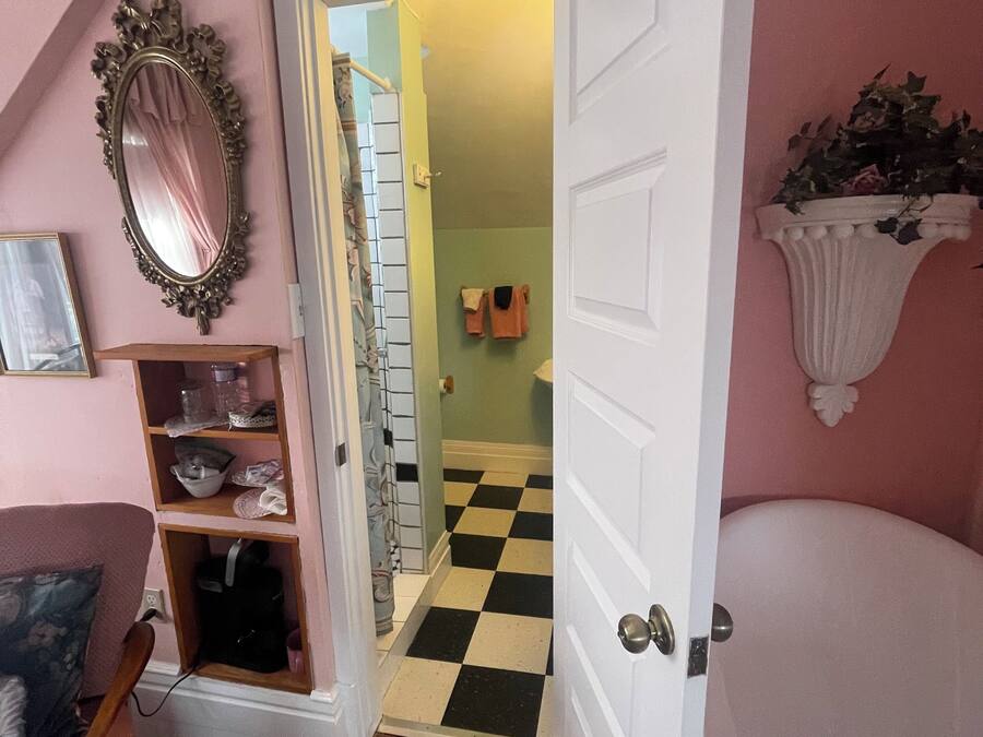 A room with a checkered floor, a white door, a mirror, and a shelf with items.