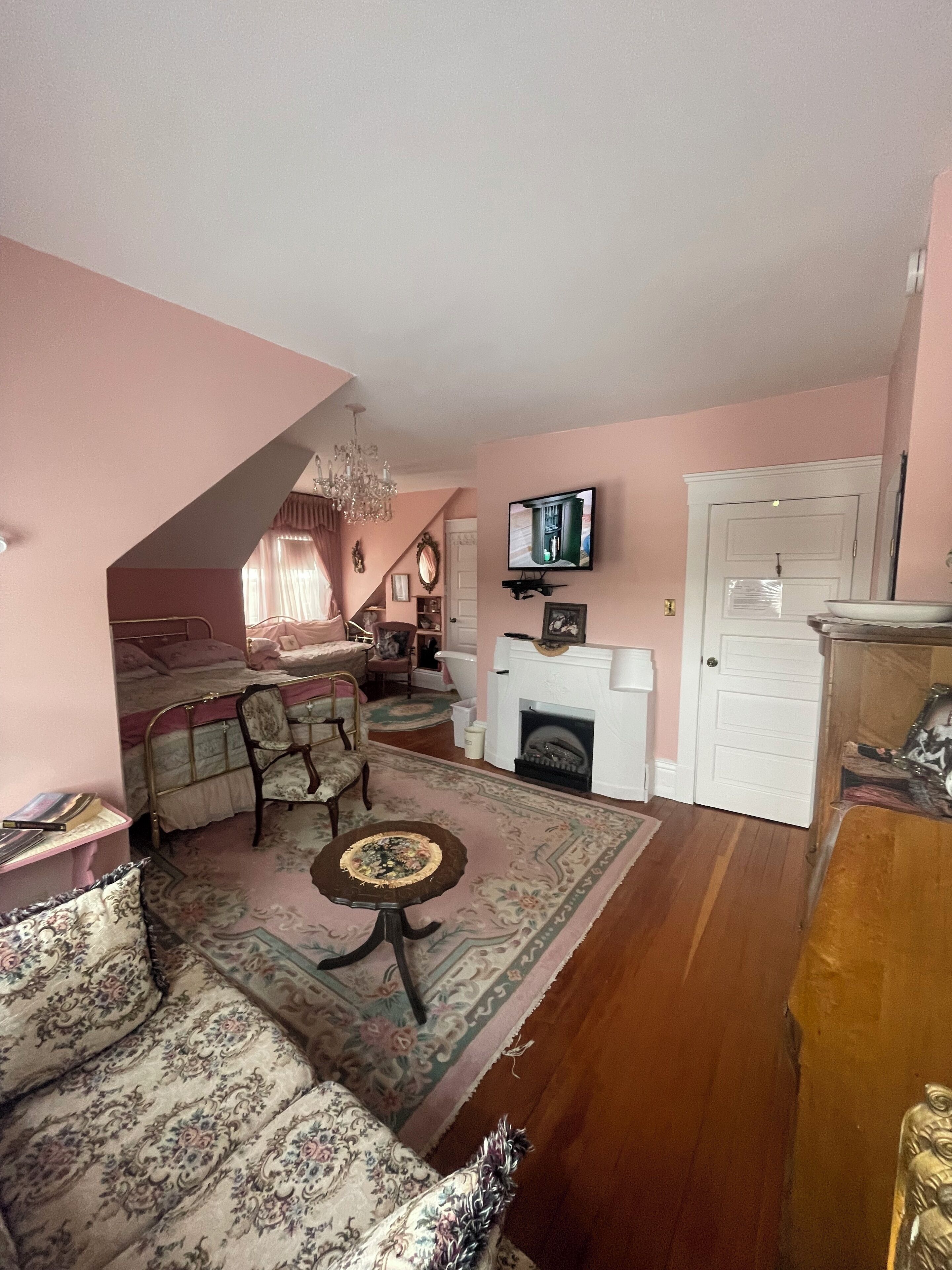 A living room with a sofa, armchairs, a coffee table, a fireplace, and a television mounted on the wall.