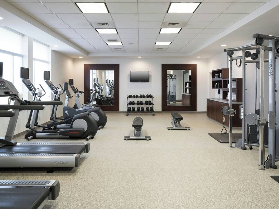 A gym with treadmills, elliptical machines, dumbbells, and weightlifting equipment.
