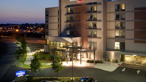 A multi-story hotel with a modern design, featuring a prominent entrance and a visible parking area.