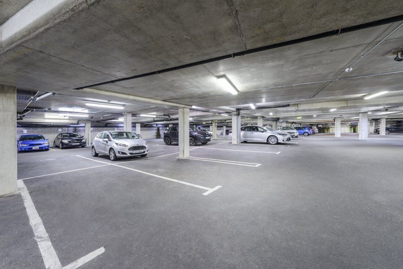 Un parcheggio sotterraneo su più livelli con pilastri in cemento e illuminazione al neon.