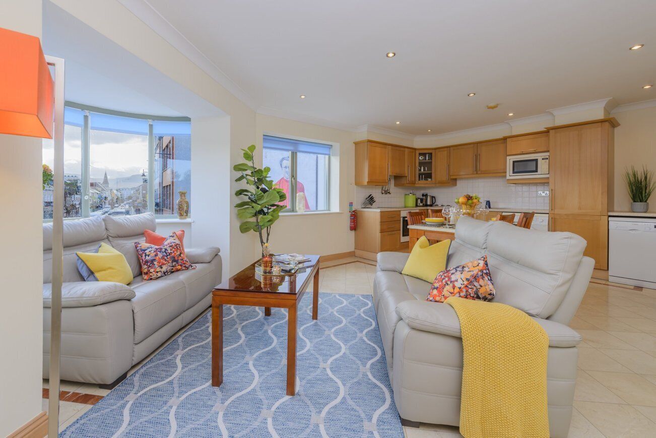 A modern living room with two sofas, a coffee table, and a view of a cityscape through large windows.