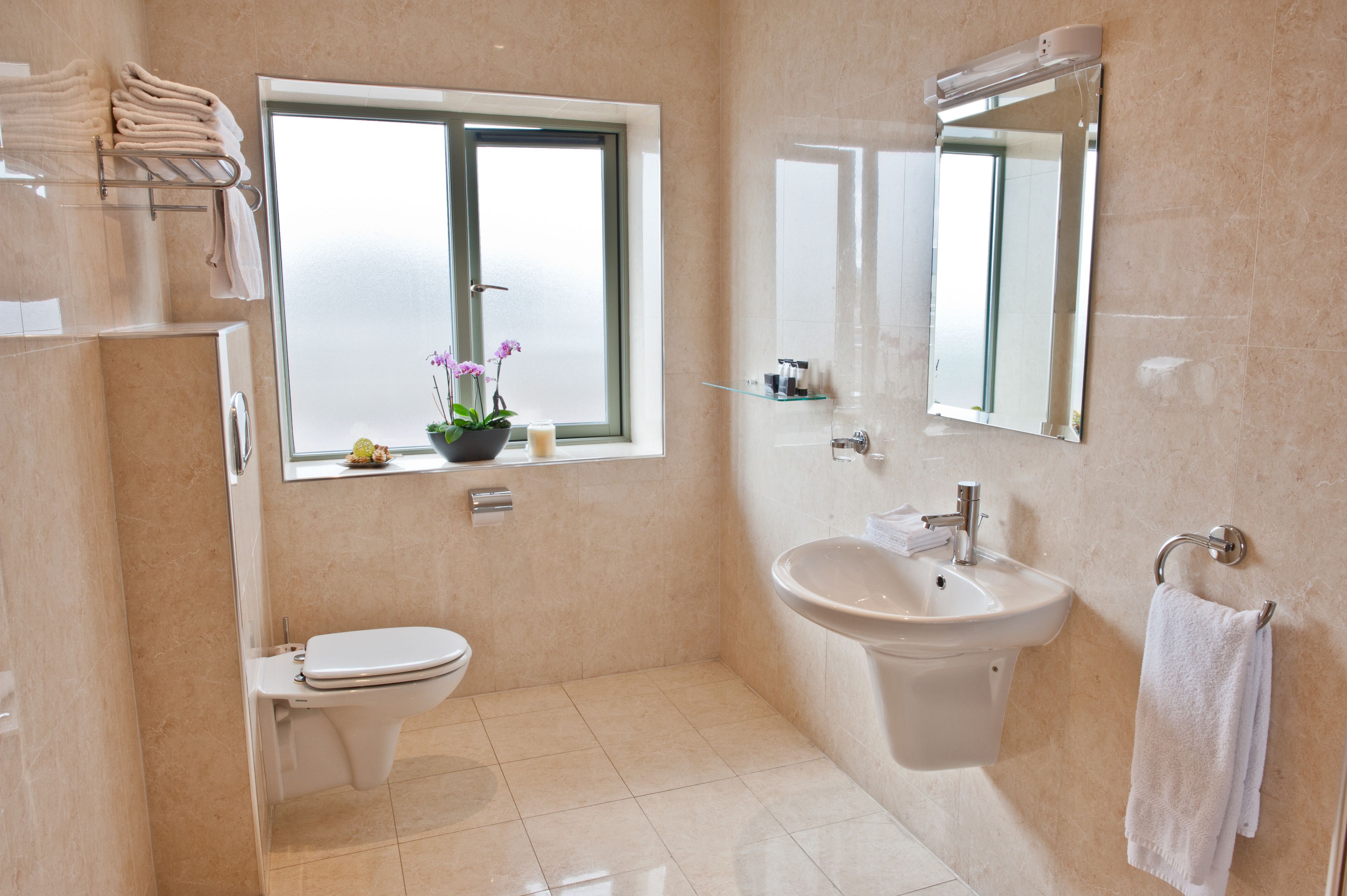 Une salle de bain moderne équipée de toilettes, d’un lavabo et d’une fenêtre donnant sur un beau paysage.