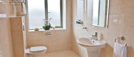 A modern bathroom with a toilet, sink, and window with a view.