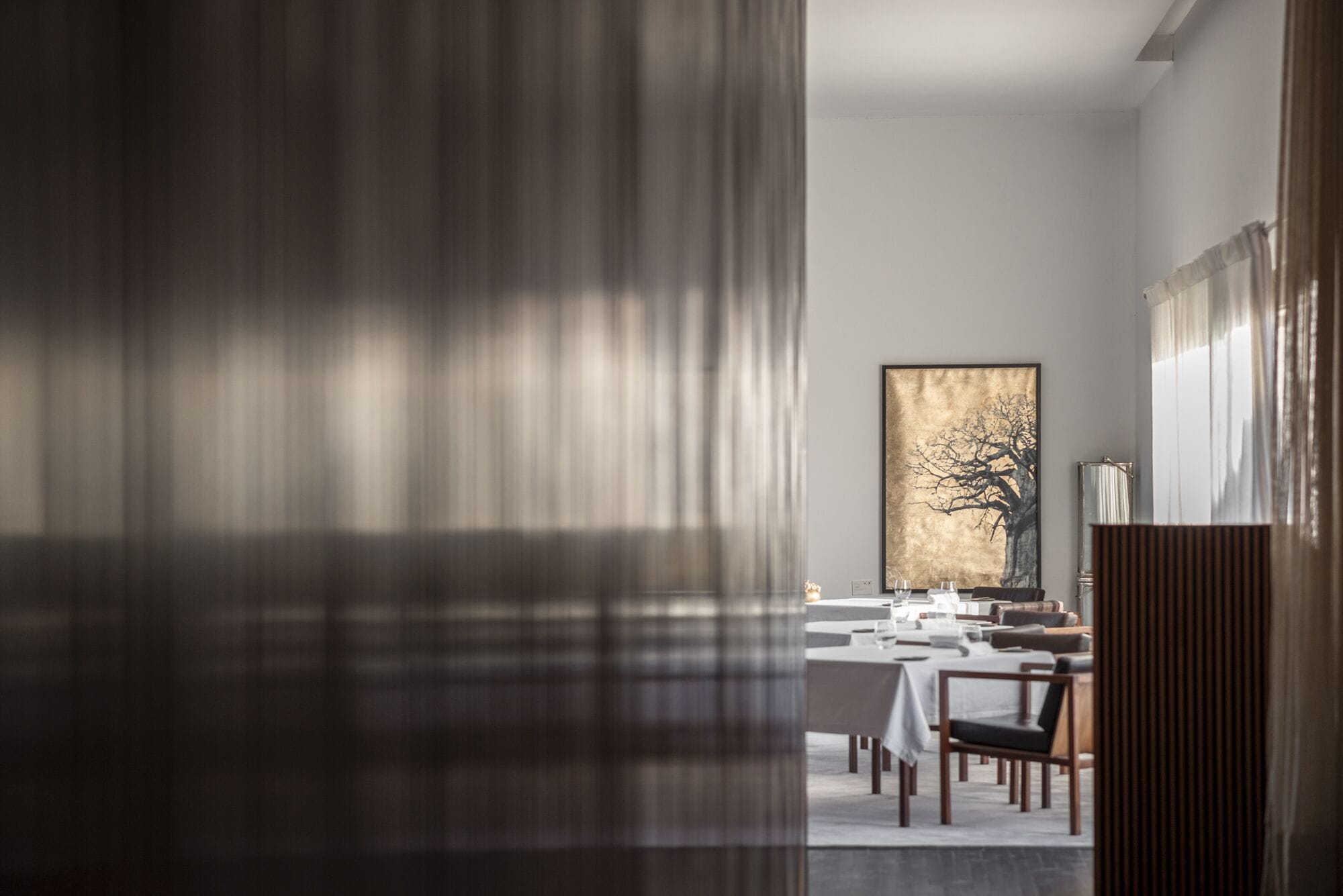 Un comedor moderno con una mesa larga, sillas y un cuadro grande en la pared.