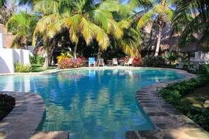 A swimming pool surrounded by palm trees and lounge chairs.