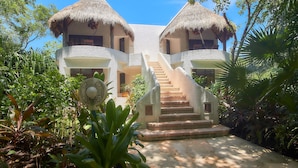 A two-story building with thatched roofs, a central staircase, and lush tropical vegetation. - Amarte Maroma Hotel Eco Boutique Spa (Playa del Carmen)