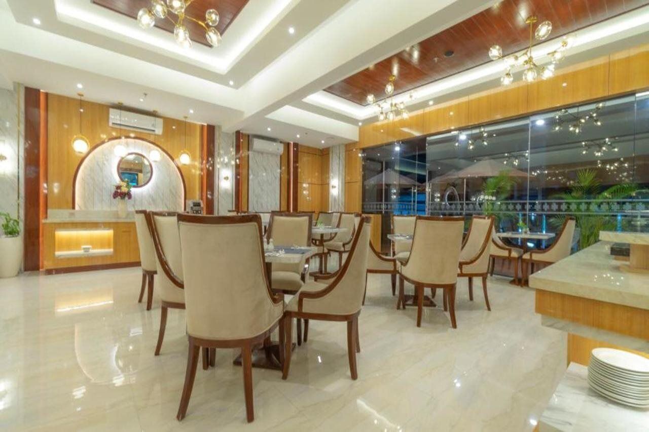 A modern hotel lobby with a reception desk, seating area, and large windows.