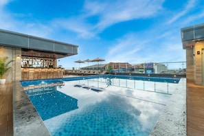 An infinity pool with a bar area and outdoor seating. - POP! Hotel Teuku Umar Denpasar - Bali (Denpasar)