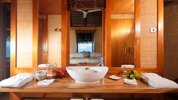 Un baño de madera con un espejo grande, un lavabo blanco y toallas.
