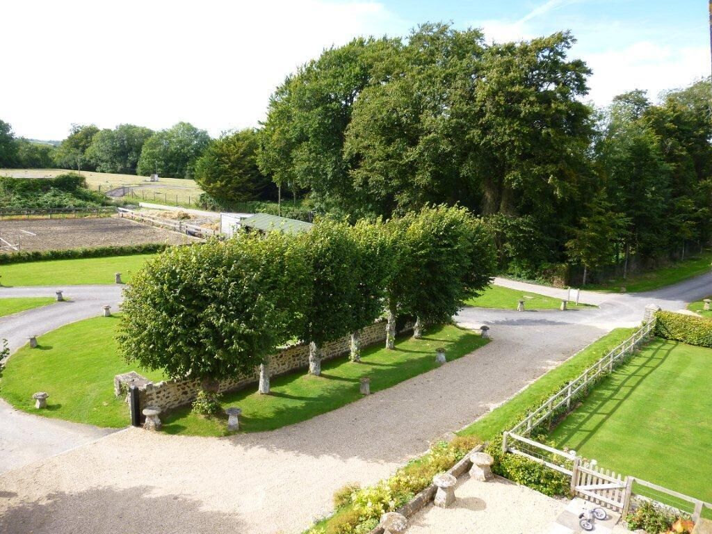 A landscaped garden with a gravel path, stone walls, and a variety of trees.