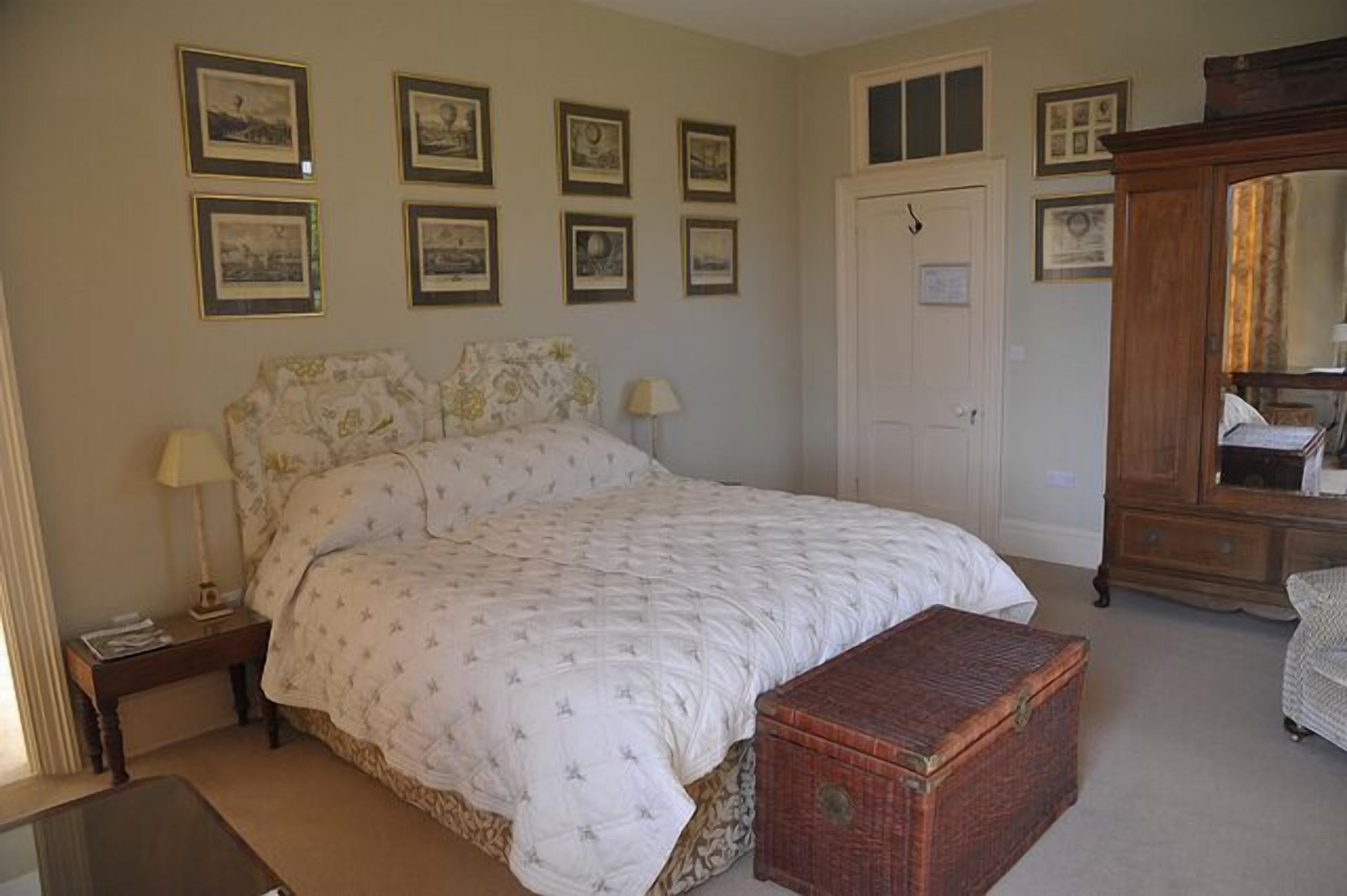 A bedroom with a bed, bedside tables, a dresser, and framed pictures on the wall.
