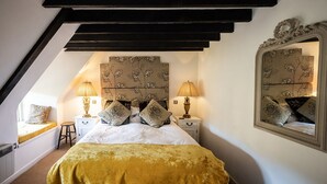 A bedroom with a bed, two nightstands, a mirror, and a window. - The Brace of Pheasants (Dorchester)
