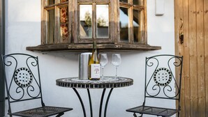 A small round table with two metal chairs, a bottle of wine, and two glasses on it. - The Brace of Pheasants (Dorchester)