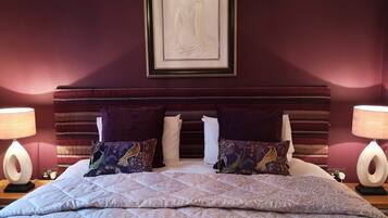 Un dormitorio con una cama, dos lámparas, una obra de arte enmarcada y una colcha estampada.
