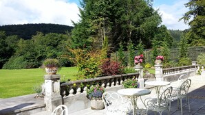 A garden with a stone railing, potted plants, and outdoor seating. - Glangwili Mansion (Carmarthen)