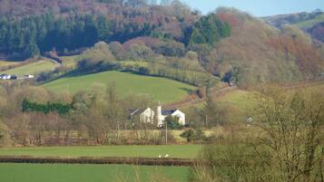 A rural landscape with rolling hills, a stone building with a tower, and a green field.