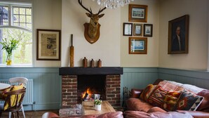 Una sala de estar acogedora con chimenea, sofá de cuero y varias fotografías enmarcadas en la pared.
