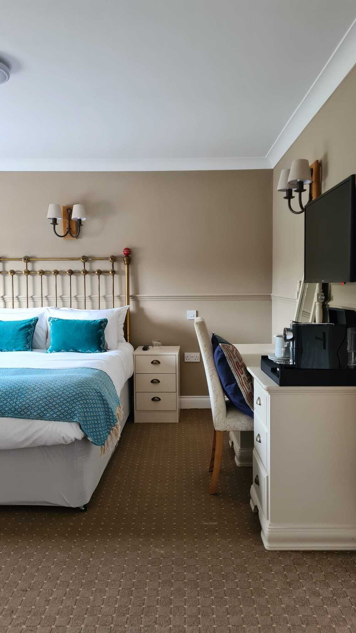 Une chambre d’hôtel comprenant un lit, des tables de chevet, un bureau avec une chaise et un téléviseur.