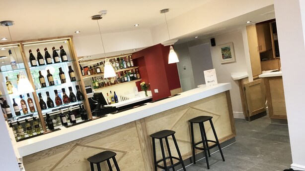 A bar area with a counter, stools, and shelves of bottles. - Gidea Park Hotel (Romford)