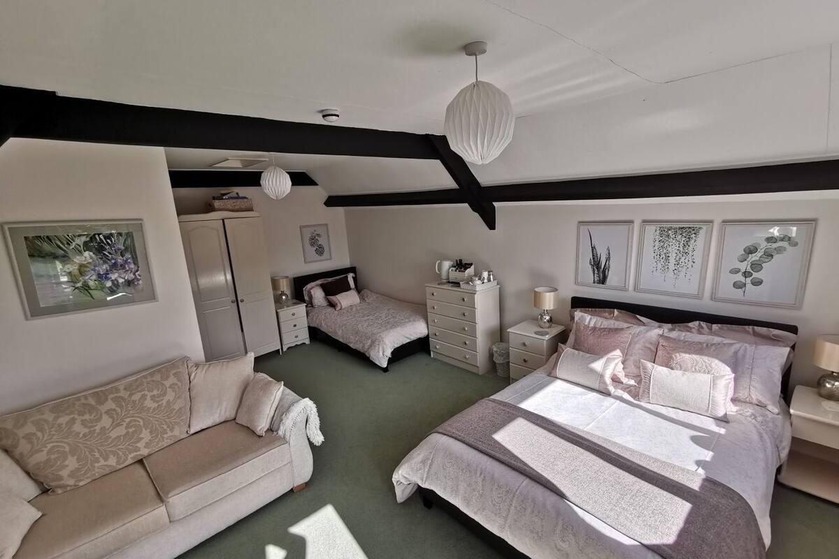 A bedroom with a large bed, a sofa, a dresser, and a nightstand.