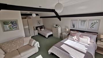 A bedroom with a large bed, a sofa, a dresser, and a nightstand.