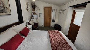 Quarto com cama, escrivaninha, cadeira, armário pequeno e porta.