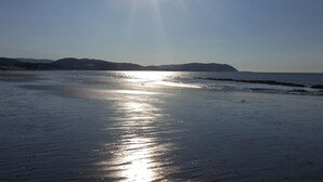 A beach with a clear sky and sunlight reflecting on the water. - Steps Farmhouse (Minehead)
