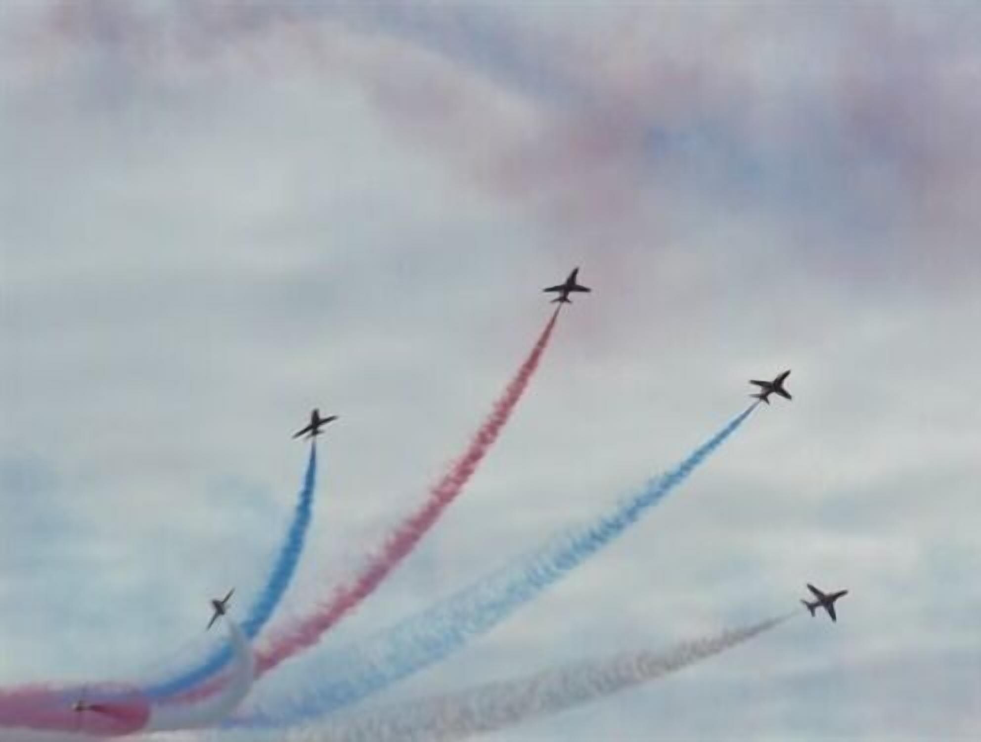 A group of jets performing an aerial maneuver with smoke trails.