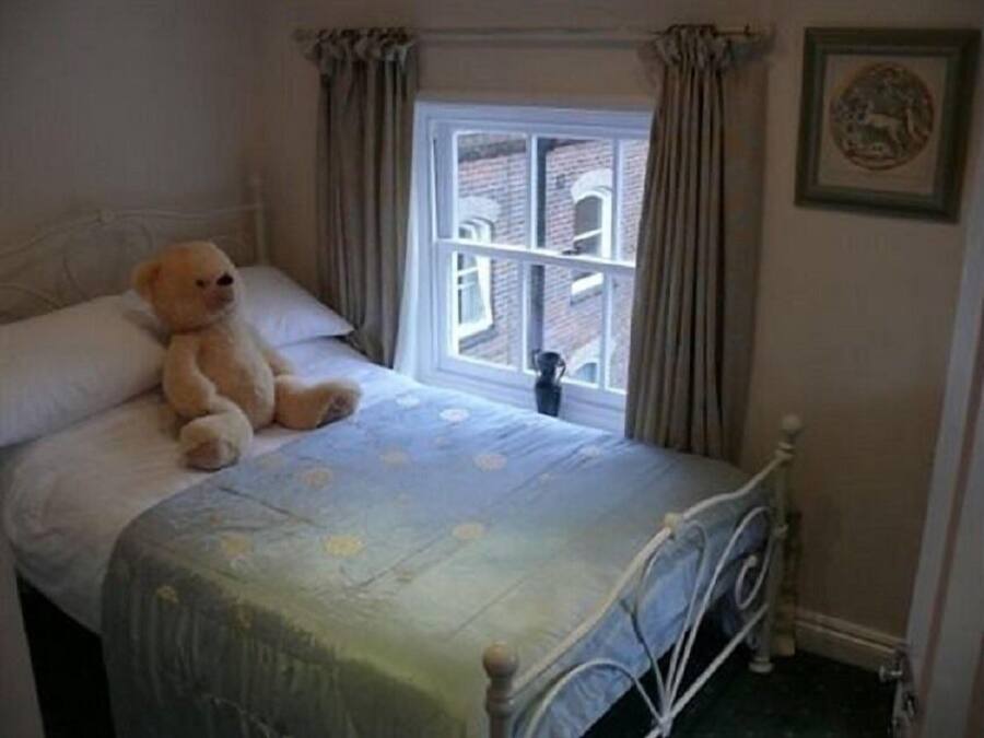 Ein Schlafzimmer mit Bett, Fenster und einem Teddybär.