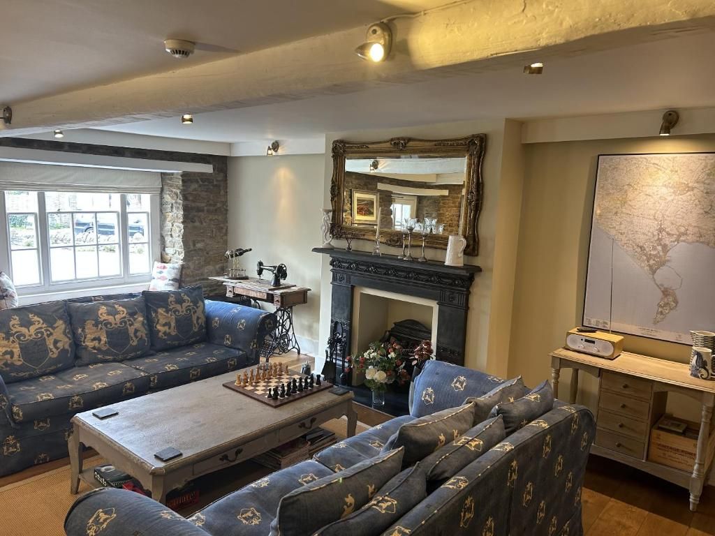 A room with a sofa set, a fireplace, a chessboard, and a map on the wall.