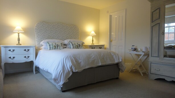 A neatly arranged bedroom with a bed, two bedside tables with lamps, a small side table, and a wardrobe. - The Heritage Bed & Breakfast (Weymouth)
