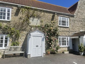 A stone building with a sign for a breakfast restaurant, a white door, and a bench outside. - The Heritage Bed & Breakfast (Weymouth)