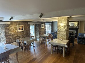 A dining area with stone walls and wooden flooring, featuring tables and chairs. - The Heritage Bed & Breakfast (Weymouth)