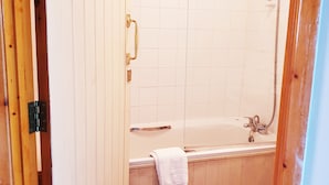 A bathroom with a bathtub, a shower, and a wooden door. - The White Horse Inn (Cambridge)