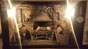 A traditional fireplace with logs, a metal grate, and a chimney. - The White Horse Inn (Cambridge)