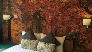 A hotel room with a bed, two nightstands, and a wall mural of autumn leaves. - The White Horse Inn (Cambridge)