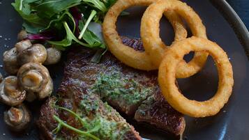 A plate with steak, mushrooms, onion rings, and a salad.