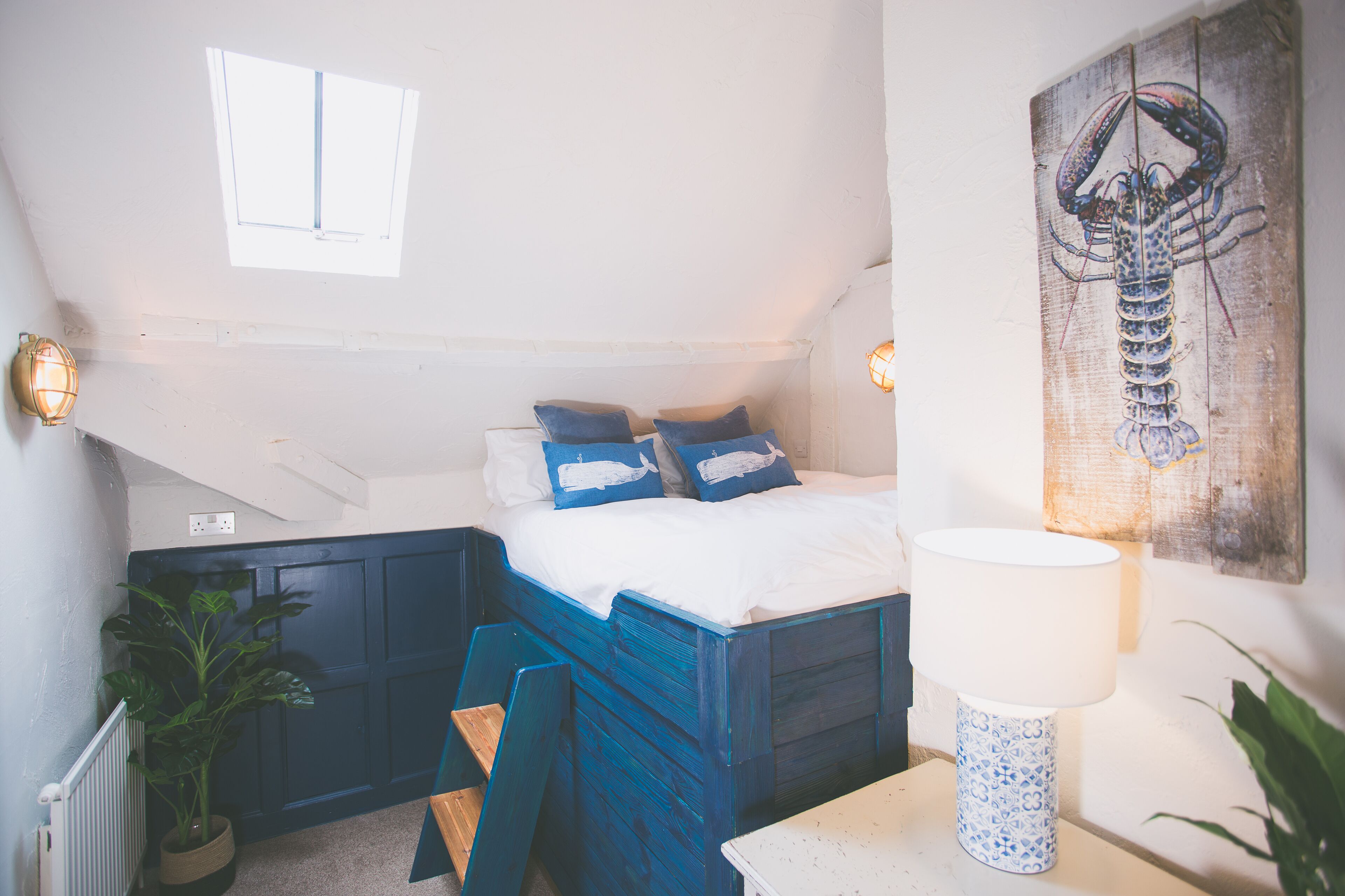 Un dormitorio con cama, mesita de noche, lámpara y una obra de arte colgada en la pared.