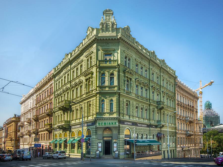Un edificio histórico con fachada verde, numerosas ventanas y una entrada destacada.