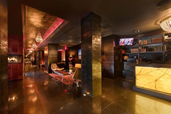 Un lobby moderno con mostrador de recepción, zona de estar y un bar.