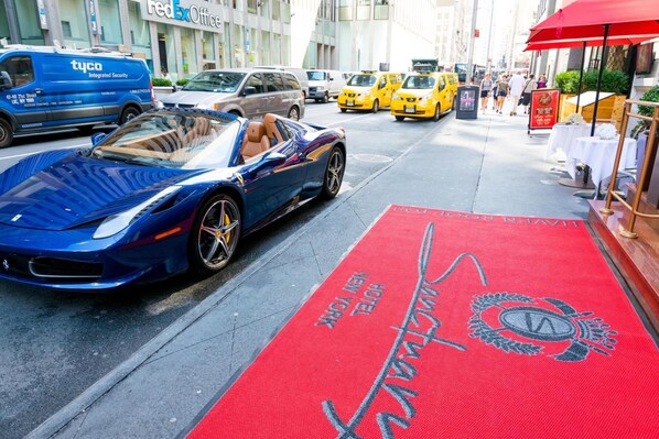 A red carpet with "Hotel New York" text and a logo, a blue sports car, and a blue van with "tyco" branding. - Sanctuary Hotel New York (New York)
